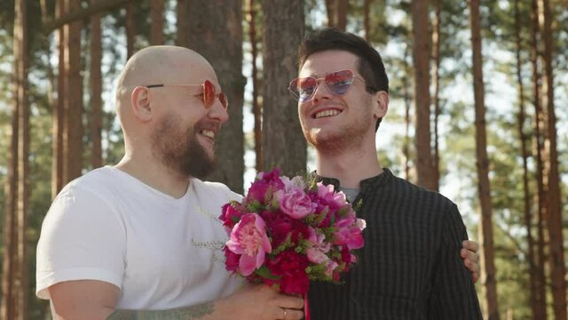 Portrait of queer couple happy together. Gay wedding concept. Two men with flower bouquet and ring on finger smile and hug. Relationship Goals. LGBTQI, Pride Event, LBGT Pride Month, Gay Pride Symbol