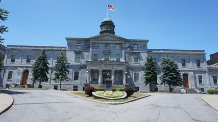 Montreal, QC/ Canada - 6/24/2020: McGill University campus. McGill university flag is on top of McCall MacBain (Arts building) with blue sky in the background.