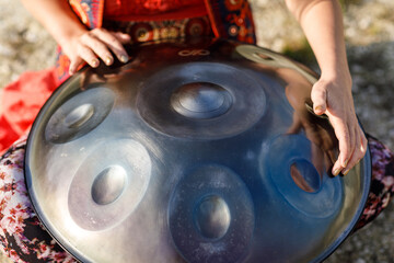 beautiful woman playing with hangdrum in nature.
