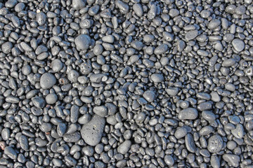 Fototapeta na wymiar Black lava rock pebbles on the beach - pattern. Big Island, Hawaii. 