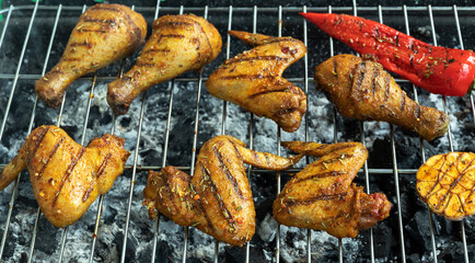 juicy golden grilled chicken legs and wings on the grill, barbecue, coals