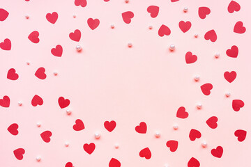 Romantic pink backround with red paper hearts and white pearls. Love, dating and Valentines Day concept, copy space