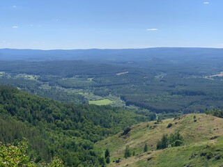 Naklejka premium Awesome panoramic view. Blue mountains and sky, green hills. A sign on the side of a mountain