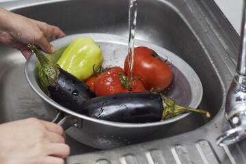 Closeup of fresh vegetables washed at a sink in a colander