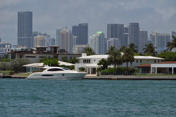 White motor yacht on Biscayne Bay cruising by luxury real estate on Rivo Alto island in Miami Beach...