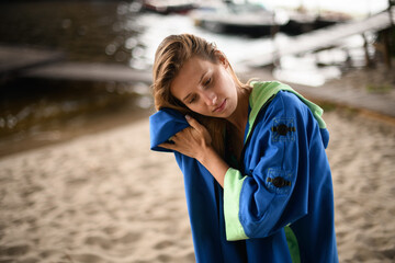Naklejka premium young woman wipe her hair with towel on background of sandy river pier
