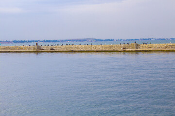 Dilapidated old fishing dock collapsing into the sea. Walking paths on the promenade. 