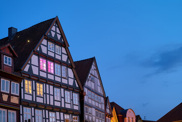 gables of traditional half-timbered houses in Celle (Germany) with pink and yellow light shining through some windows during blue hour at dawn