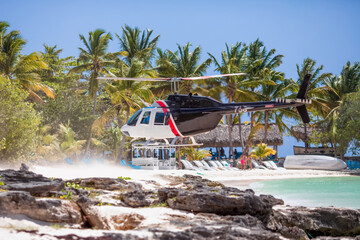 Blue helicopter landing on tropical caribbean beach during private excursion in Dominican republic to Saona island © Irina