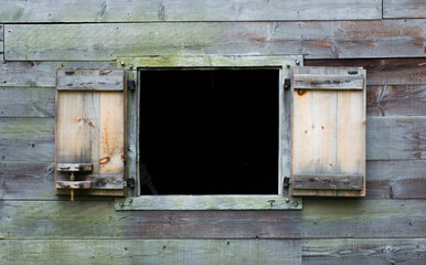exterior wooden wall of a vintage colonial New England cabin with an open shutter window and copy space