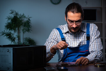Young male technician repairing computer in workshop at night