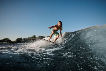 Fototapeta na wymiar Active young man balancing on wake board down the river waves