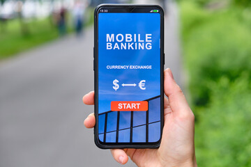 Mobile banking interface with currency exchange function in smartphone and holding by hand.