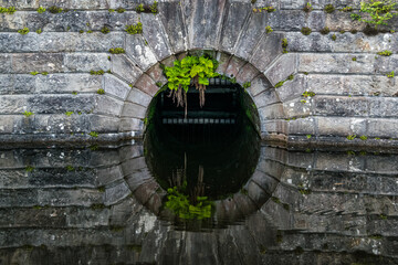 Detail of an old stone dam reflecting in water at Milngavie Waterworks, the water treatment facility located in Milngavie, Scotland.