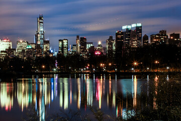 View from central park showing new york city skyline with skyscrapers visible with a reflection from water