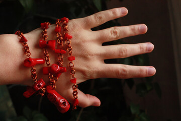Red beads made of natural coral and copper wire on a female hand .