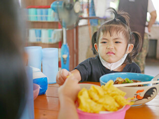 Little baby girl reaching her hand out for the same piece of deep fried wantan as taken by her...