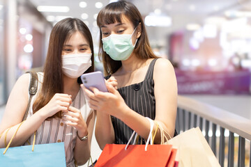Asian woman wearing face mask. Happy woman with shopping bags enjoying in shopping. Girl holding...