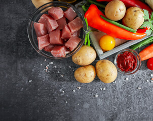 three potatoes with meat and vegetables on a stone background and with place for text on the left, close-up top view.