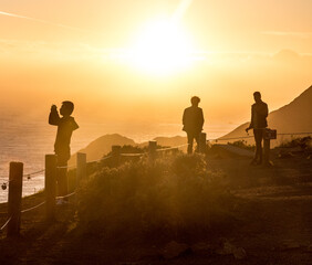 Photographers overlooking san francisco bay in silhouette against setting golden sun
