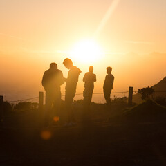 Photographers overlooking san francisco bay in silhouette against setting golden sun