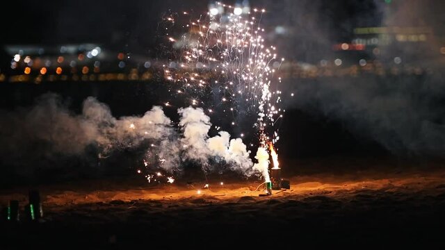 Small white and green firework burning and exploding on the beach