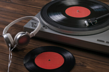 White headphones and a vinyl record player on a wooden background.