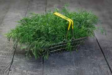 A large amount of dill in a basket on a black wooden table.