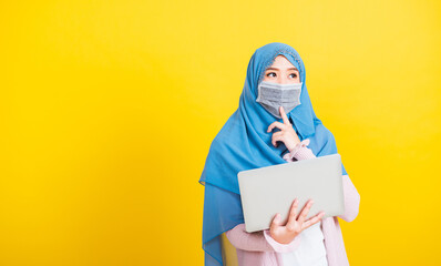 Asian Muslim Arab, Portrait of happy beautiful young woman Islam religious wear veil hijab and face mask protect she quarantines disease coronavirus hold laptop computer and thinking question - Powered by Adobe