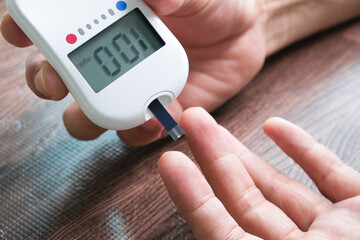 hand of people check diabetes and high blood glucose monitor with digital pressure gauge. Healthcare and Medical concept