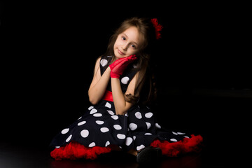 Girl dressed in retro fashion clothes sitting on a black background.