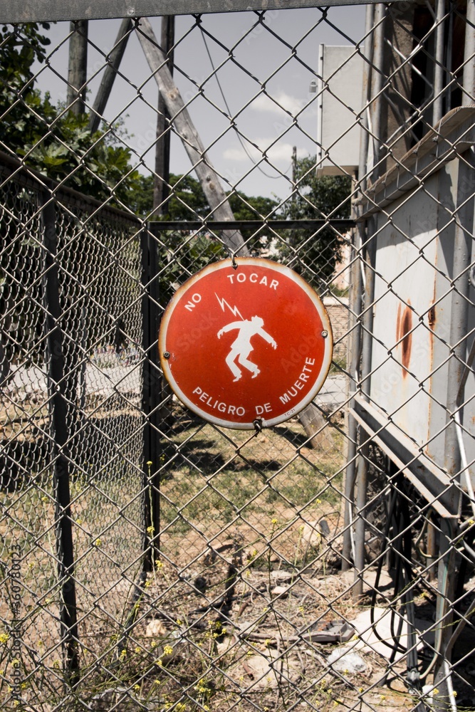 Sticker Sign on the fence in Spanish warning people of high electrical voltage