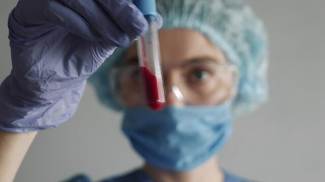 Closeup of microbiologist or medical worker hand with blue surgical gloves looking blood test result as positive for the new rapidly spreading Coronavirus. pandemic and epidemic COVID.