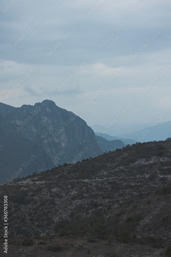 Wall mural Vertical shot of rocky landscape under the cloudy sky