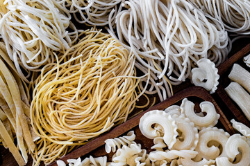 Varieties of dry pasta on a wooden plate
