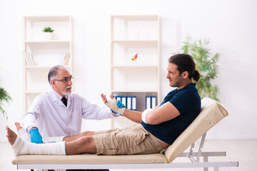 Fototapeta premium Young injured man visiting old doctor traumatologist