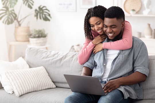 Happy African American Couple Browsing Internet On Laptop At Home