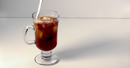 A person making an ice coffee on a white background