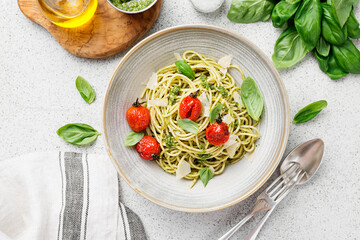 Pasta spaghetti with pesto sauce and fresh basil leaves in gray bowl. Light grey background