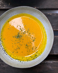 Golden pumpkin soup on wooden table.