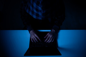Dark shot , top view of a hacker in a hood hacking or doing something on laptop 
