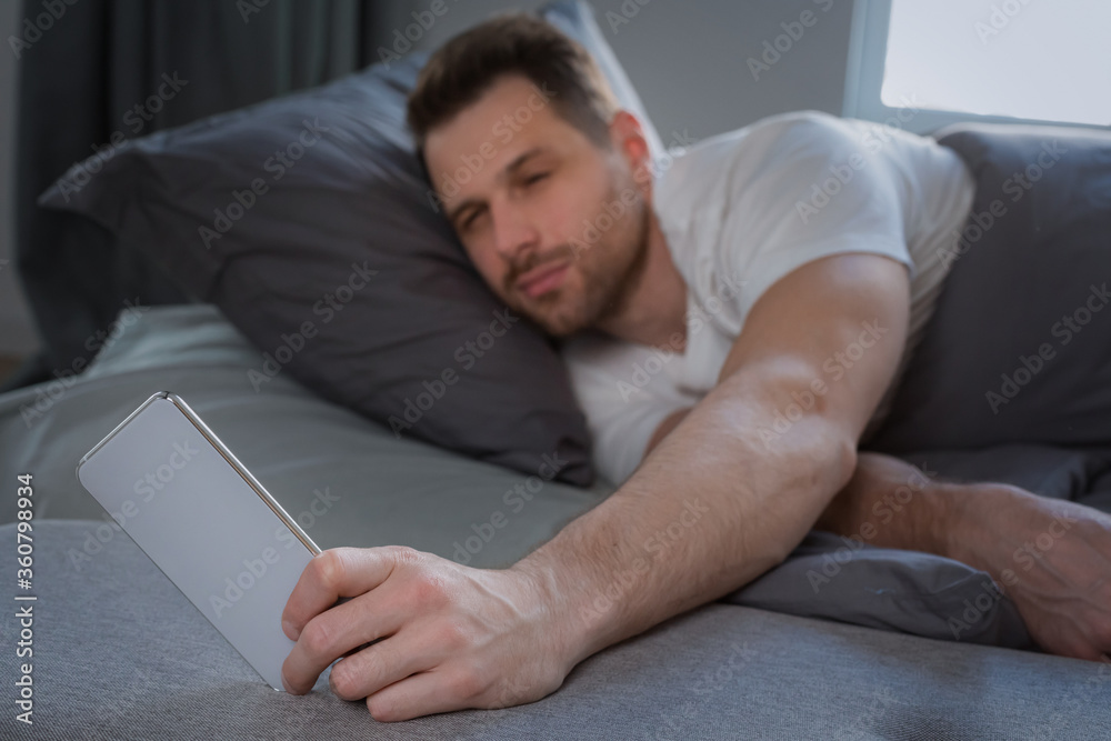 Aufkleber Man Using Smartphone Waking Up Lying In Bed At Home