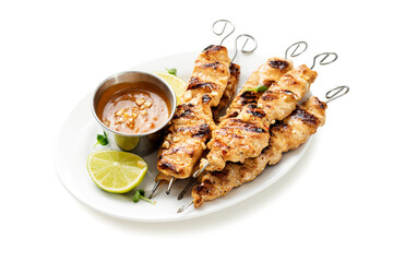 Grilled chicken satay skewers with peanut butter sauce isolated on white background