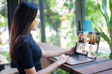 Young Woman is looking at her computer screen while business meeting through video conferencing application - obrazy, fototapety, plakaty