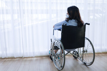 A patient or alone woman sitting on wheelchair and looking through out the widow, hopeless or sadness feeling 