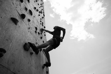 Sportsman climber on steep rock, climbing on artificial wall. Extreme sports and bouldering concept.