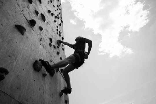 Sportsman climber on steep rock, climbing on artificial wall. Extreme sports and bouldering concept.