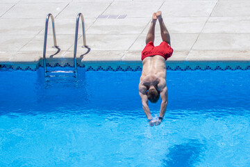 hombre de bañador rojo tirándose de cabeza a la piscina