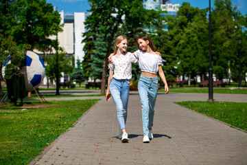 Fototapeta na wymiar Two happy girlfriends teenagers are walking in the summer park.