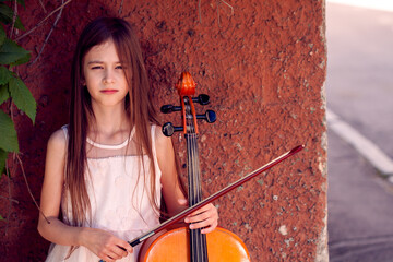 beautiful girl in a pink dress stands with a cello © Fotograf